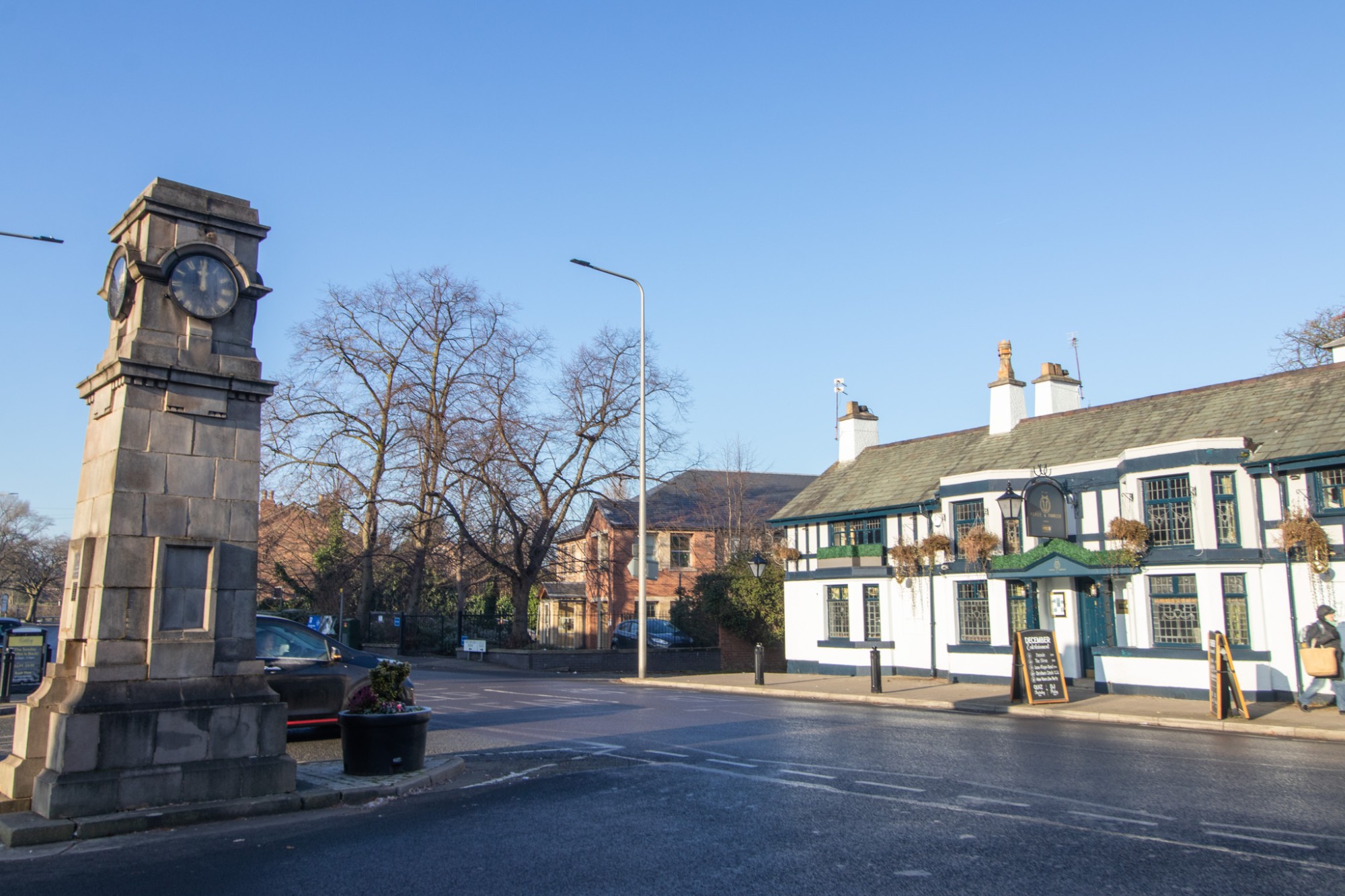 Gatley village centre with the war memorial clock tower and a traditional pub
